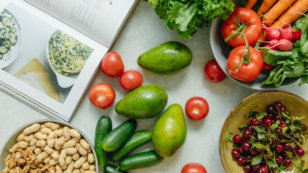 Abgebildet sind einige gesunde Zutaten, die auf einer Arbeitsplatte in einer Küche zubereitet werden, inklusive offenes Kochbuch. Ernährung und Schlaf.